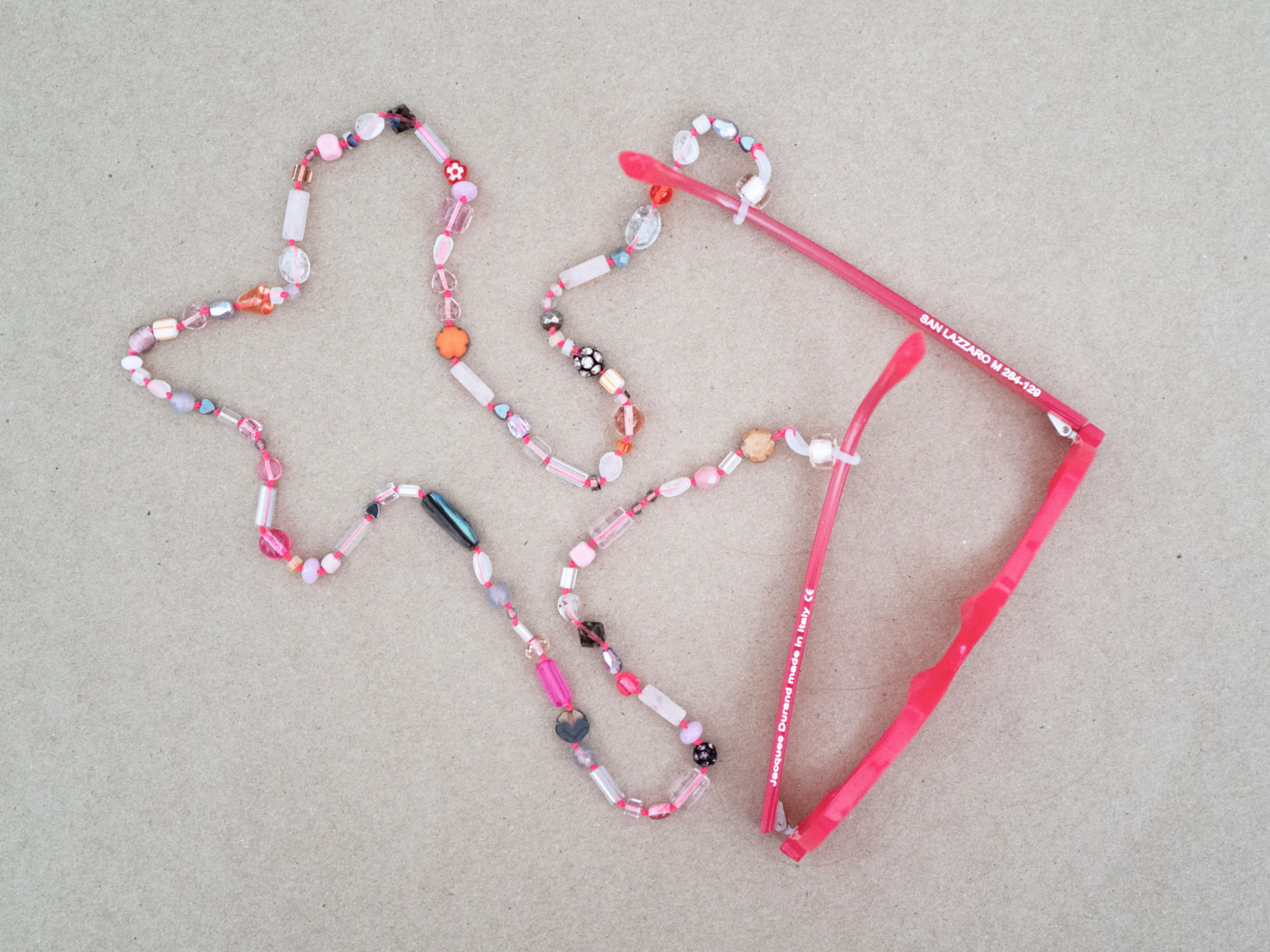 Pink glasses chain with red glasses on concrete